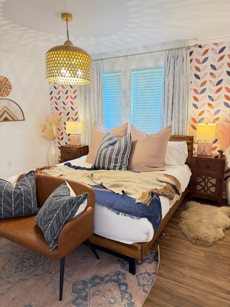 Fredericksburg rental bedroom with a brass pendant, leather reading chair, and soft Hill Country light through the curtains.