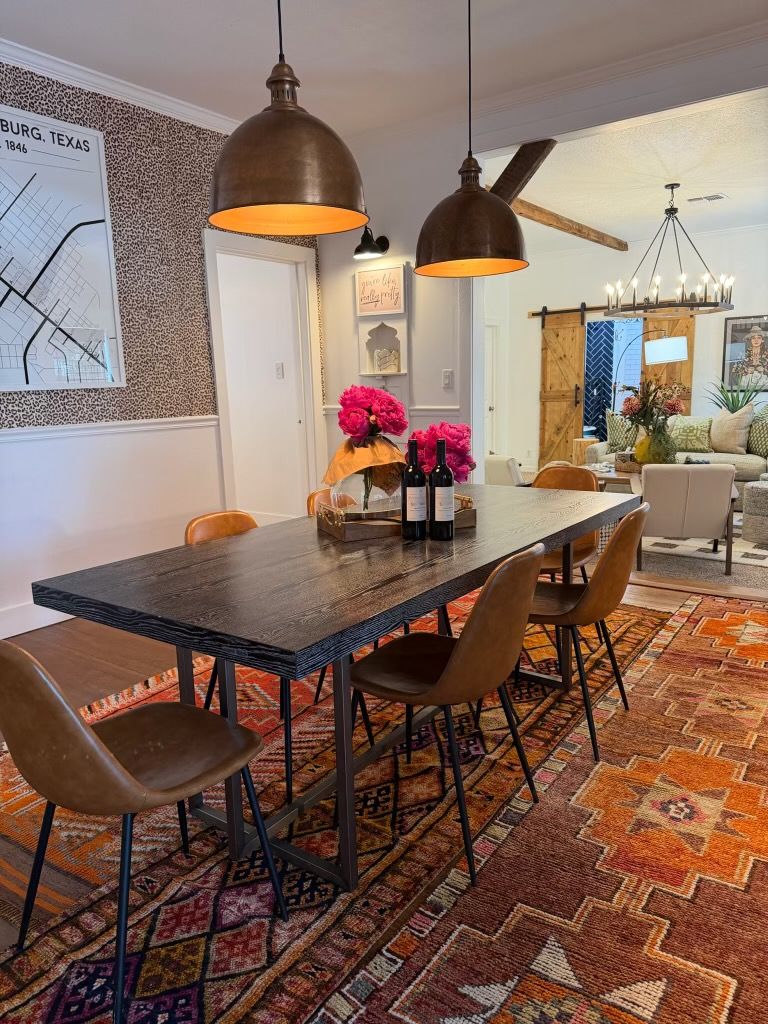 Fredericksburg rental dining room with a long dark wood table, leather chairs, bronze pendants, and a Fredericksburg, Texas map on the wall.