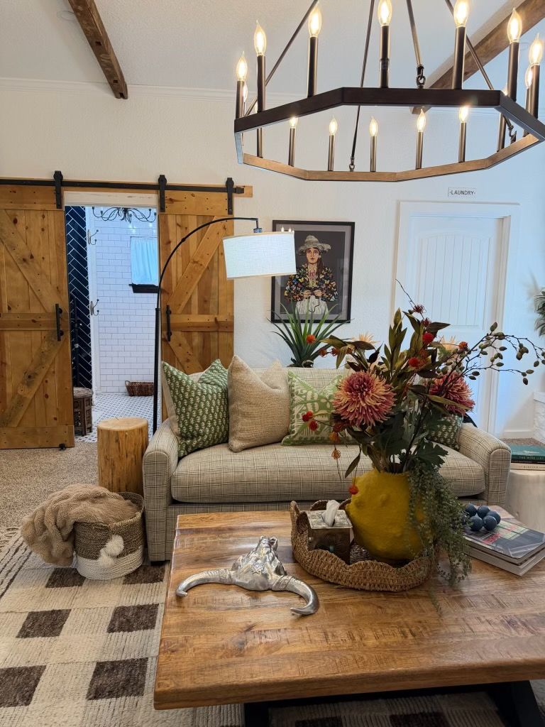 Fredericksburg rental living room with a wagon-wheel chandelier, a checked sofa, and sliding barn doors.